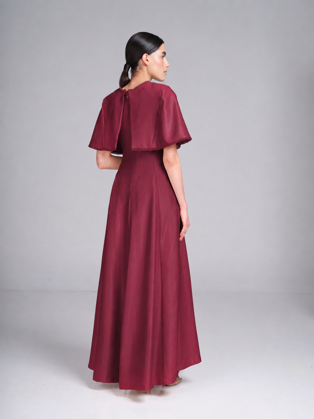Maroon cape evening gown with beaded neckline and cape trim