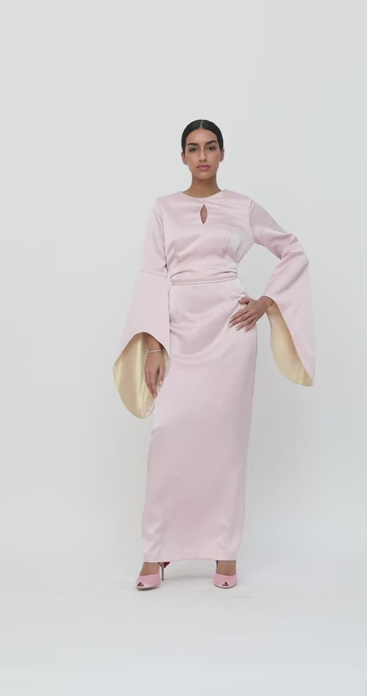 Video of the Alchemilla Dress in pink, showing the wide sleeves and the back slit in movement as the model walks, by Baruni